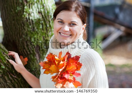 Beautiful girl in the autumn park collects red and yellow leaves