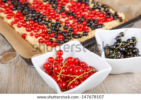 Fresh red and black currant berries with home baked cake on background