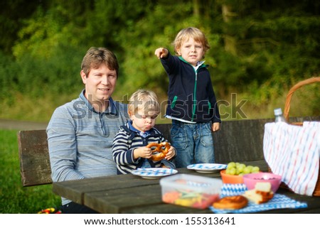Young father and two little boys picnicking in the park in summer