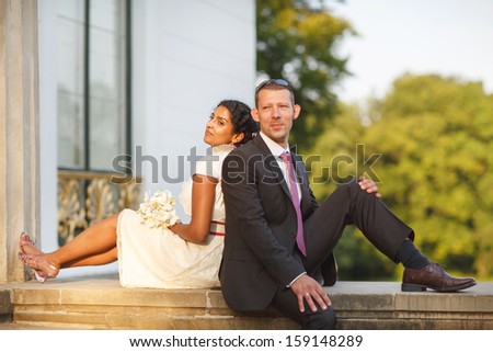 Beautiful indian bride and caucasian groom in summer park