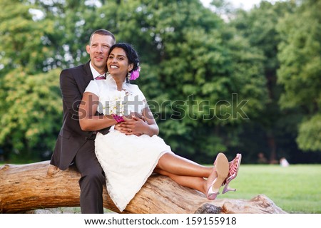 Beautiful indian bride and caucasian groom, in summer park