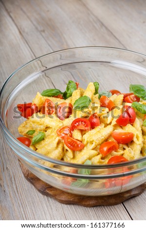 Home made tomato pasta on plate with fresh basil leaves on wooden background