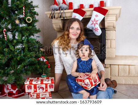 Young beautiful woman and little girl with Christmas tree and decoration.