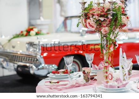 Table set  for wedding or event party with rose and berry decoration with vintage car on background