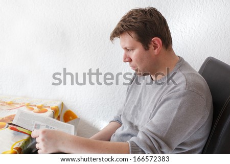 Portrait of a young man reading a magazine in kitchen