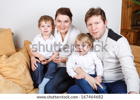 Happy family of a four having fun at home. In blue jeans and white shirts