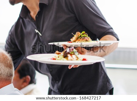 Waiter carrying a plate with salad dish on a wedding