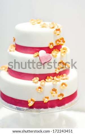 Wedding cake decorated with pink rose flowers and hearts