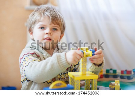 Little toddler boy playing with wooden toy, indoors.