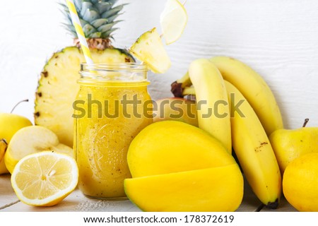 Fresh organic yellow smoothie with banana, apple, mango, pear, pineapple and lemon as healthy drink