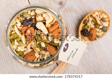 Homemade healthy cereals muesli with different nuts and oats in jar on wooden background
