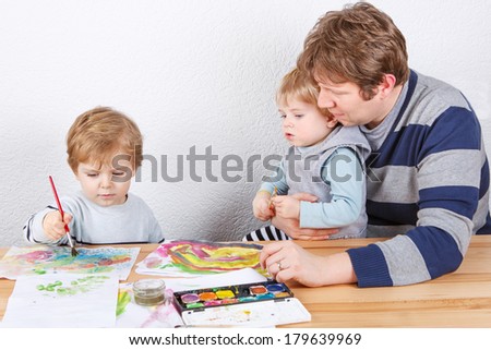 Happy family of three: Father and two little boys siblings having fun painting at home
