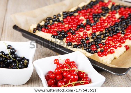 Fresh red and black currant berries with home baked cake on background