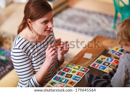 Mother and little son playing together education card game for children.
