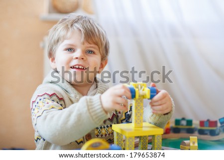 Little toddler boy playing with wooden toy, indoors.