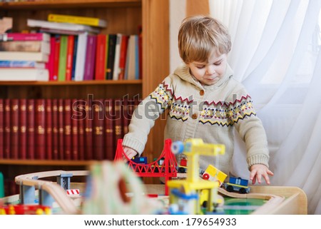 Little toddler boy playing with wooden railway, indoors.