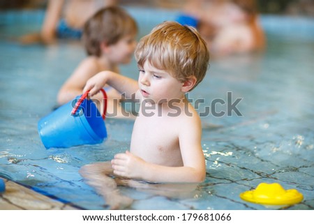 Activities on the pool, toddler boy swimming, having fun and playing in water, indoor