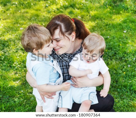 Happy caucasian family of three: Young mother and two little sibling boys in summer park, Europe