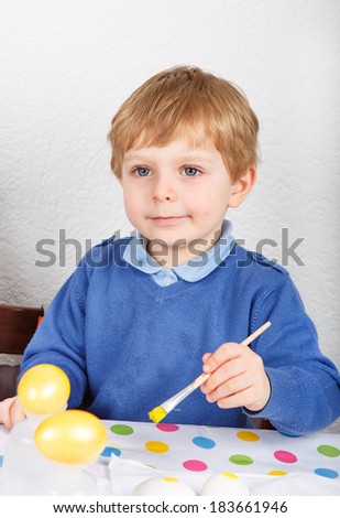 Little toddler boy painting colorful eggs for Easter hunt, traditional action in Germany for Eastern holiday, indoors