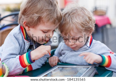 Two little sibling boys having fun together with tablet pc