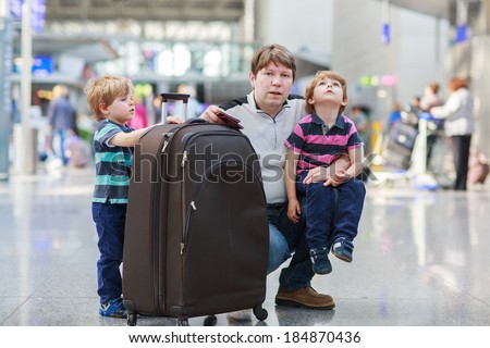 Happy family of three: Father and two little sibling boys at the airport, traveling together.