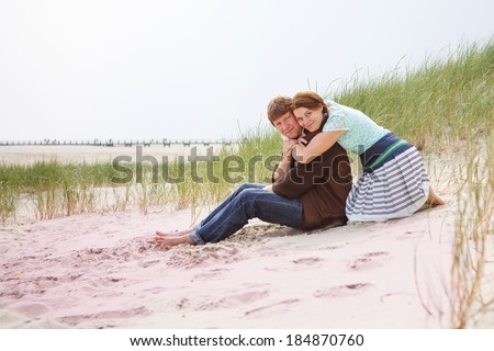 Young happy couple in love having fun on white sand dunes of the beach of North Sea