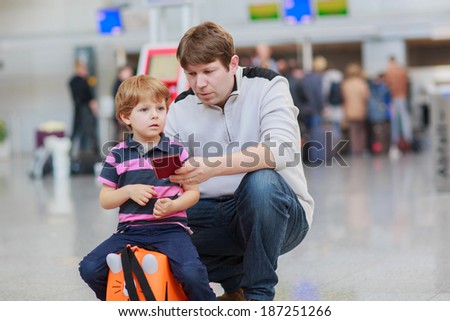 Happy family of two: Father and little son at the airport, traveling together and holding passport in hand.