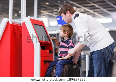 Happy family of two: Father and little son at the international airport, traveling together and checking in at terminal.