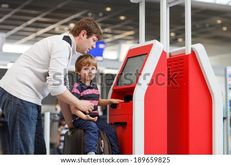 Happy family of two: Father and little son at the international airport, going on journey together and checking in at terminal.