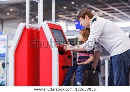 Happy family of two: Father and little son at the international airport, going on journey together and checking in at terminal.