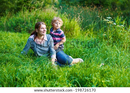 Little boy and his mother having fun together in nature landscape