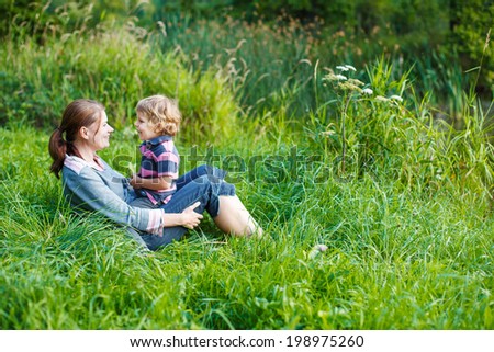 Little boy and his mother having fun together in nature landscape