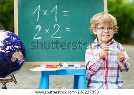 Little child at blackboard practicing mathematics, outdoor school or nursery. Back to school concept
