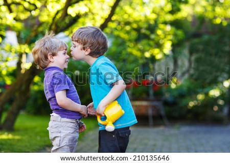 Two little sibling boys hugging and having fun outdoors, in home\'s garden. Brother love.