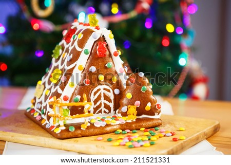 Gingerbread house with Christmas tree and lights on background