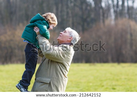 Happy grandfather and his little grandson having fun together outdoors