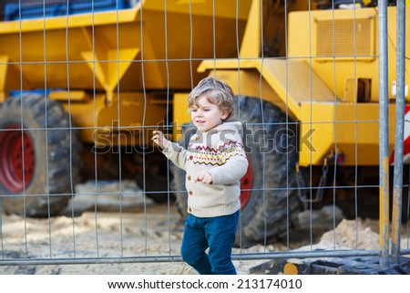 Little boy watching excavator on construction zone, outdoors