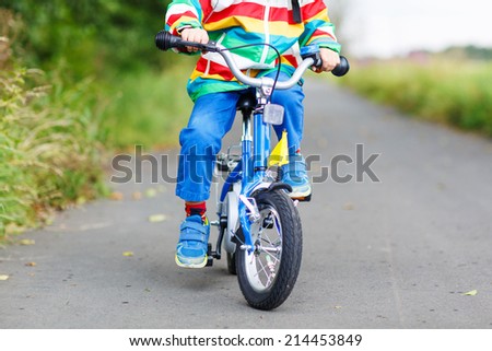 Child in colorful raincoat riding his first bike. Body and bicycle parts.