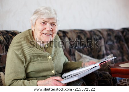 Old beautiful senior woman of 85 years reading book, indoors.