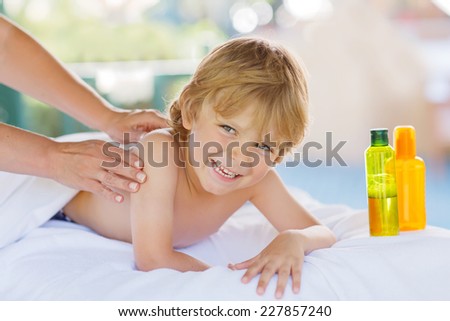 Adorable little blond kid relaxing in spa with having massage.