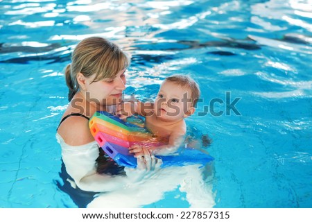 Little baby boy and his mother learning to swim in an indoor swimming pool. Having fun together. Baby swimming concept.
