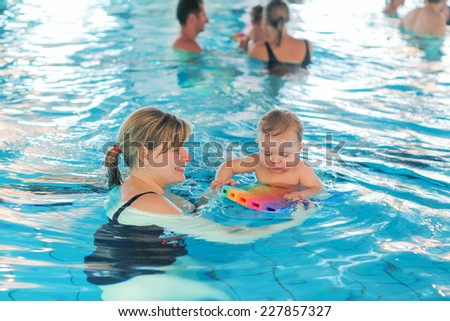 Little baby boy and his mother learning to swim in an indoor swimming pool. Having fun together. Baby swimming concept.