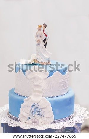 Wedding cake in soft blue and white, with bride and groom figure on the top.