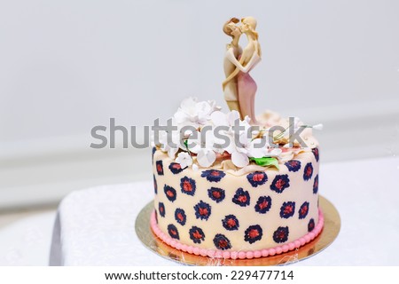 Wedding cake in soft creme, pink, with bride and groom figure on the top.