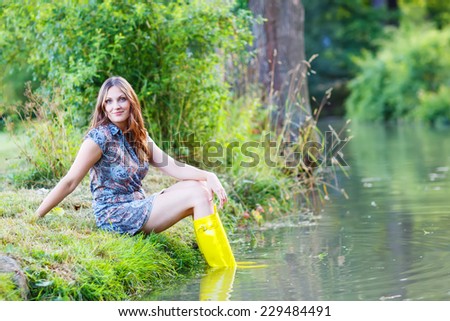 Young beautiful woman sitting in yellow rain rubber boats by a river in summer.
