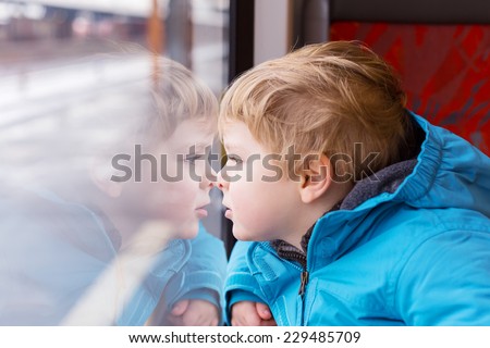 cute child looking out train window outside, while it moving. Going on vacations and traveling by railway in winter.