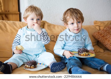 Two little kid boys eating sweet cakes together. Family of two brothers.