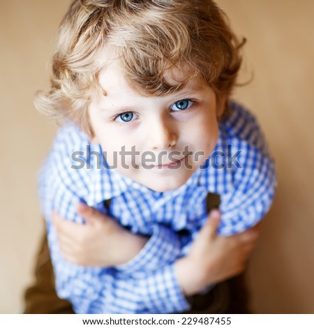 Portrait of adorable little boy with blond hairs and blue eyes, indoor.