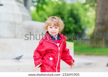 Cute little blond boy catching and playing with pigeons on a city place
