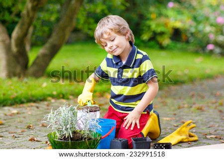Adorable little blond boy of 3 or 4 years gardening and planting flowers in home\'s garden or farm, on warm sunny day. Outdoors. Environment concept.